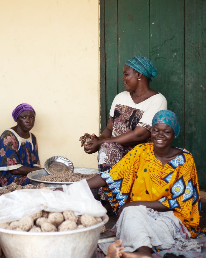 Women preparing food outdoors in Tamale, Ghana, with a focus on traditional cooking practices.